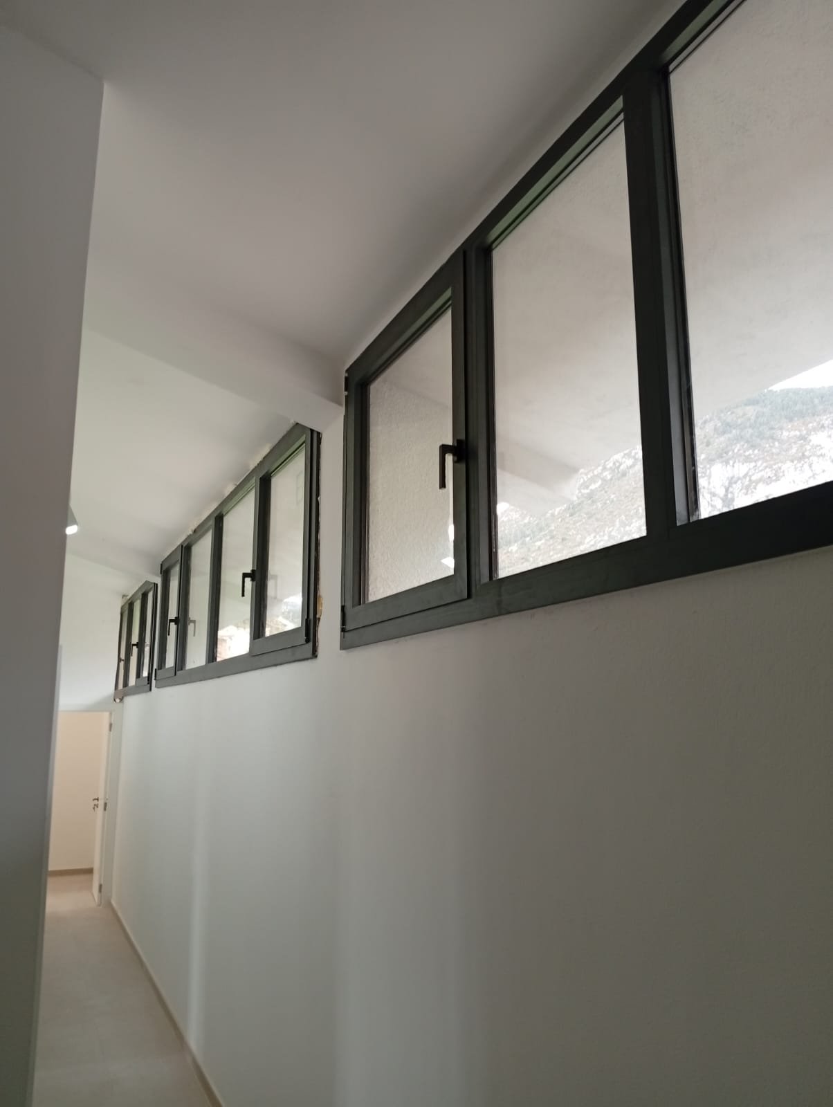 Ventanas abatibles de aluminio en la franja superior de un pasillo