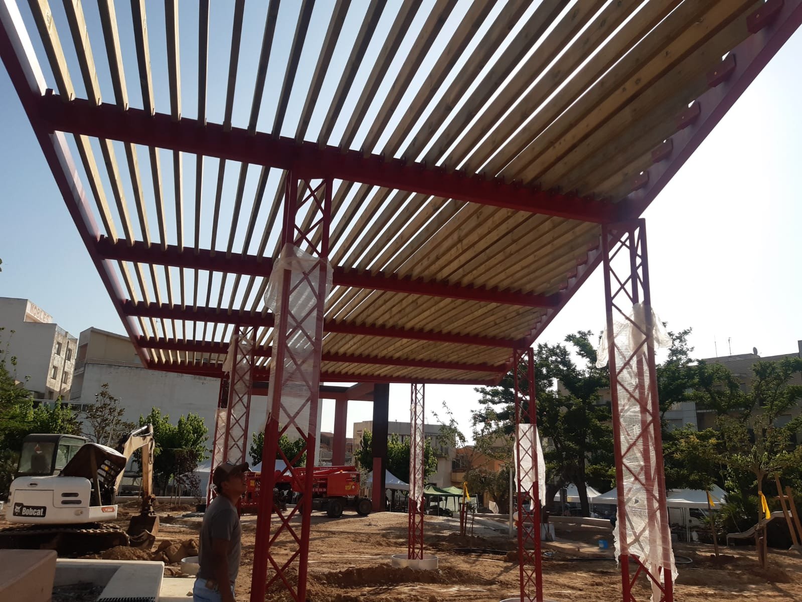 Pérgola de estructura de acero rojo con techo de listones de madera
